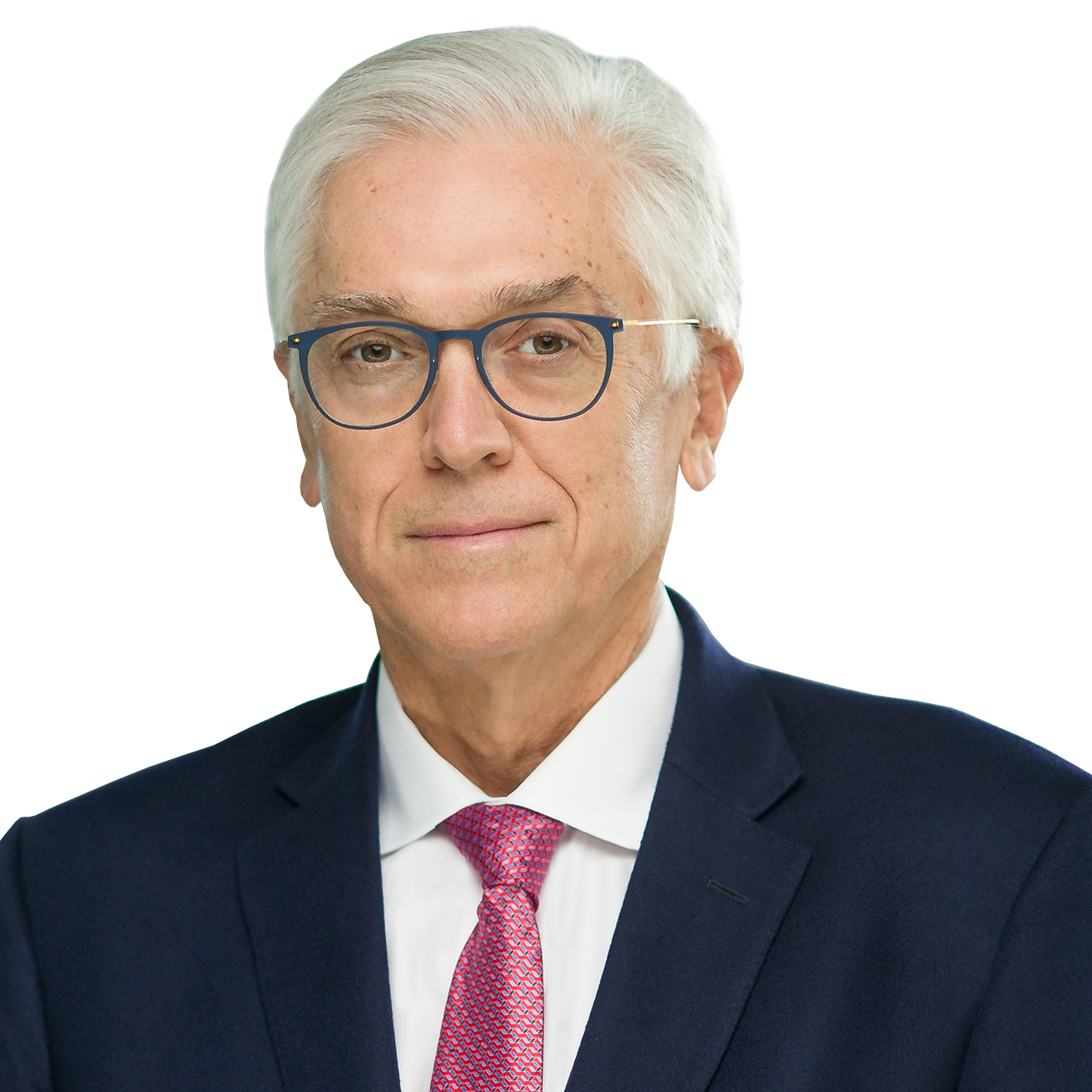 A man with white hair and glasses is wearing a dark suit, white shirt, and red tie, posing against a white background.