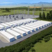 A large outdoor energy storage facility with numerous white battery units arranged in rows. Adjacent to the battery units are electrical substations with metal structures and power lines. The facility is surrounded by green fields and trees, with mountains visible in the background under a clear blue sky.
