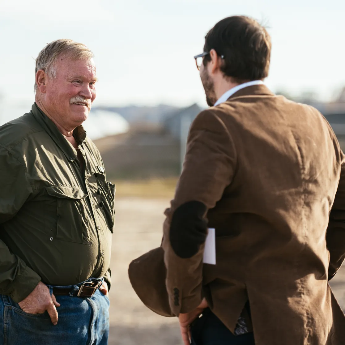 Two professionals having a discussion at an AES renewable energy site, with solar panels and construction equipment in the background.