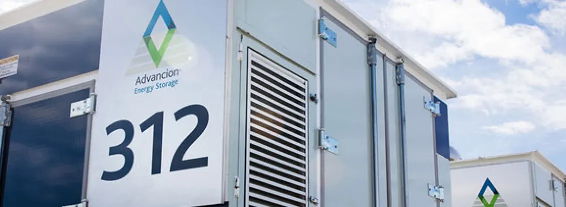 A close-up view of an Advancion Energy Storage unit with the number 312 displayed prominently. The unit features a logo and ventilation panels. The sky is partly cloudy in the background.