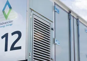 A close-up view of an Advancion Energy Storage unit with the number 312 displayed prominently. The unit features a logo and ventilation panels. The sky is partly cloudy in the background.