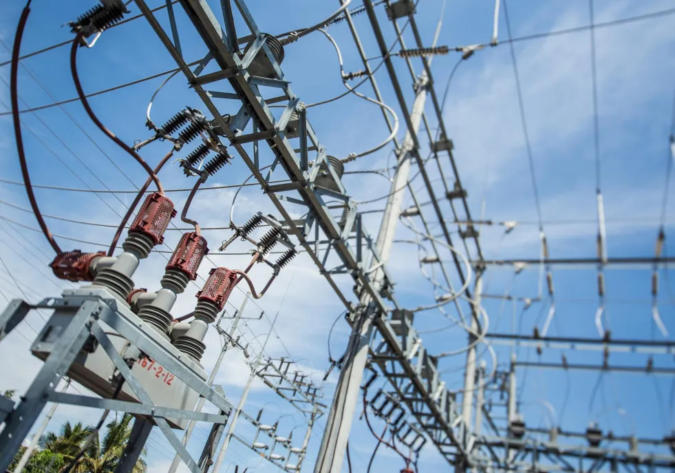 Close-up view of electrical power lines and equipment against a blue sky.