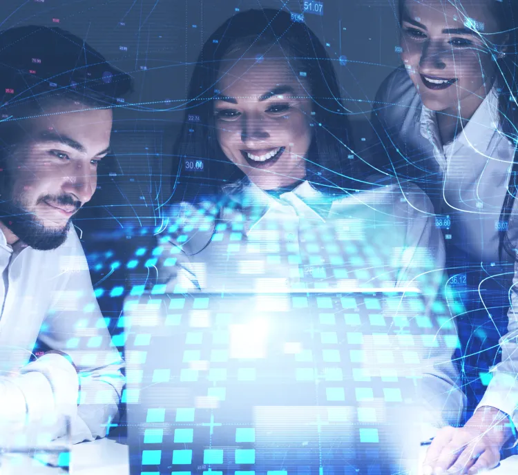 Three smiling professionals collaborate around a laptop with digital data graphics and blue network lines overlay, symbolizing teamwork and technology.