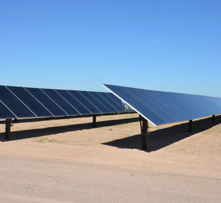 Rows of solar panels in a desert landscape under a clear blue sky.