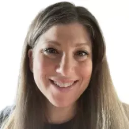 A person with long brown hair smiling at the camera against a white background.