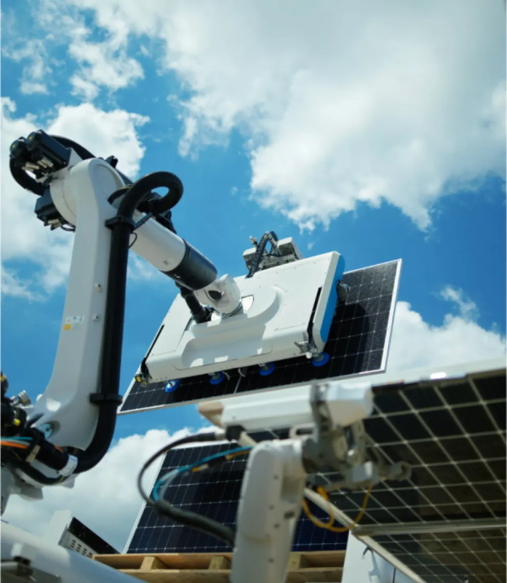 A robotic arm cleaning a solar panel under a blue sky with clouds.