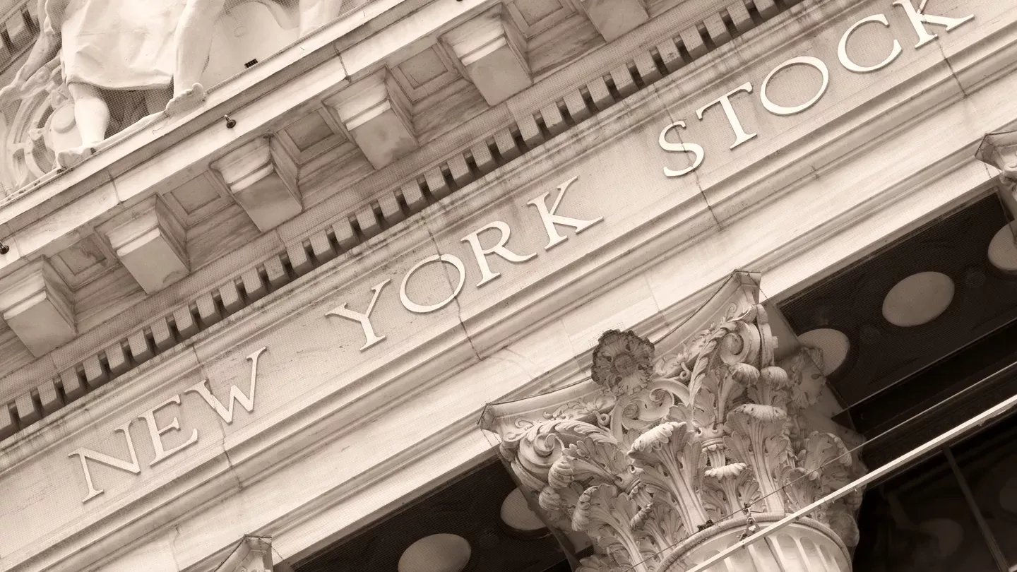 Sepia-toned close-up of the New York Stock Exchange building facade, featuring intricate architectural details and a Corinthian column.