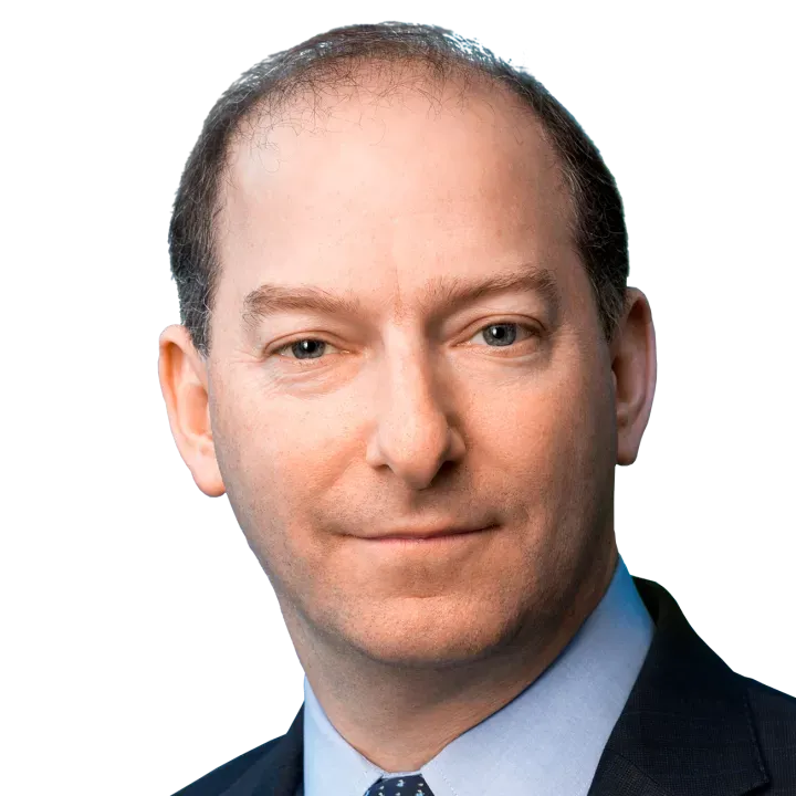 Portrait of a man in a suit and tie against a black background.