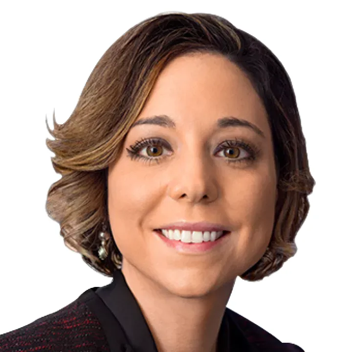 Portrait of a smiling person with short, wavy hair wearing a dark jacket against a white background.