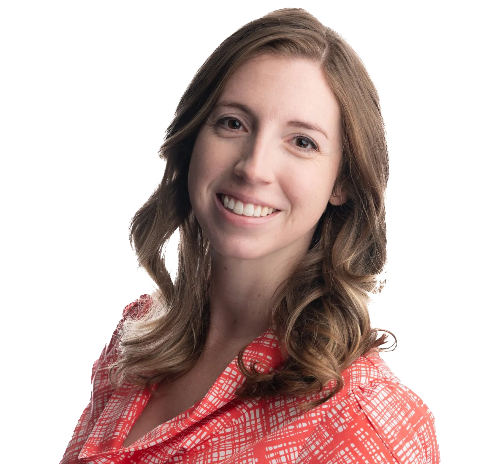 Smiling woman with wavy brown hair wearing a red patterned blouse, posing against a white background.
