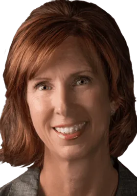 Portrait of a woman with shoulder-length brown hair and a friendly smile, wearing a gray blazer.
